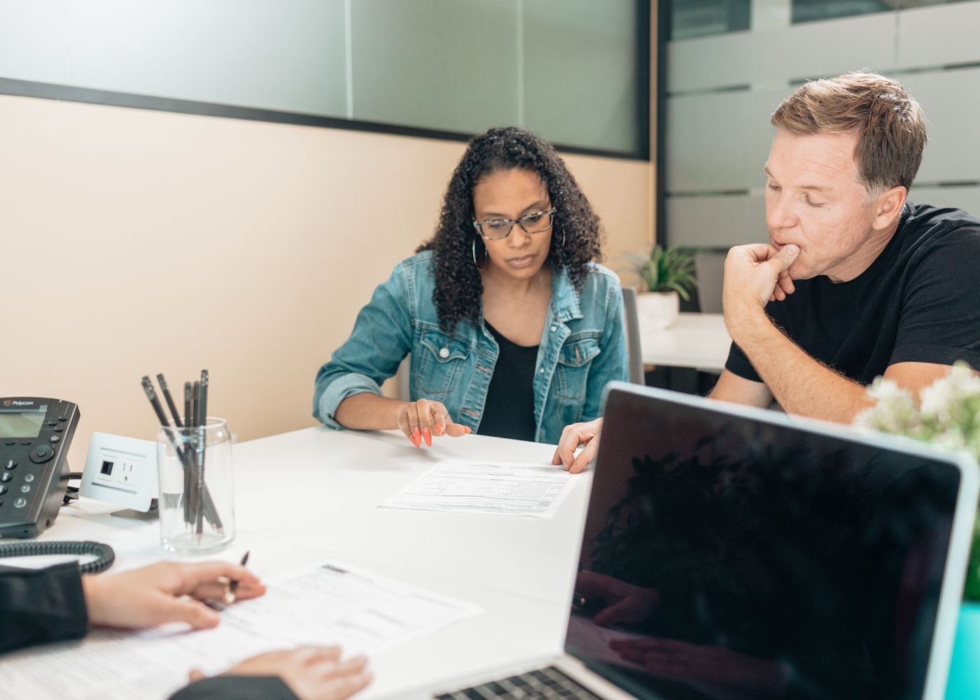 A broker going through loan documents with two clients at a desk