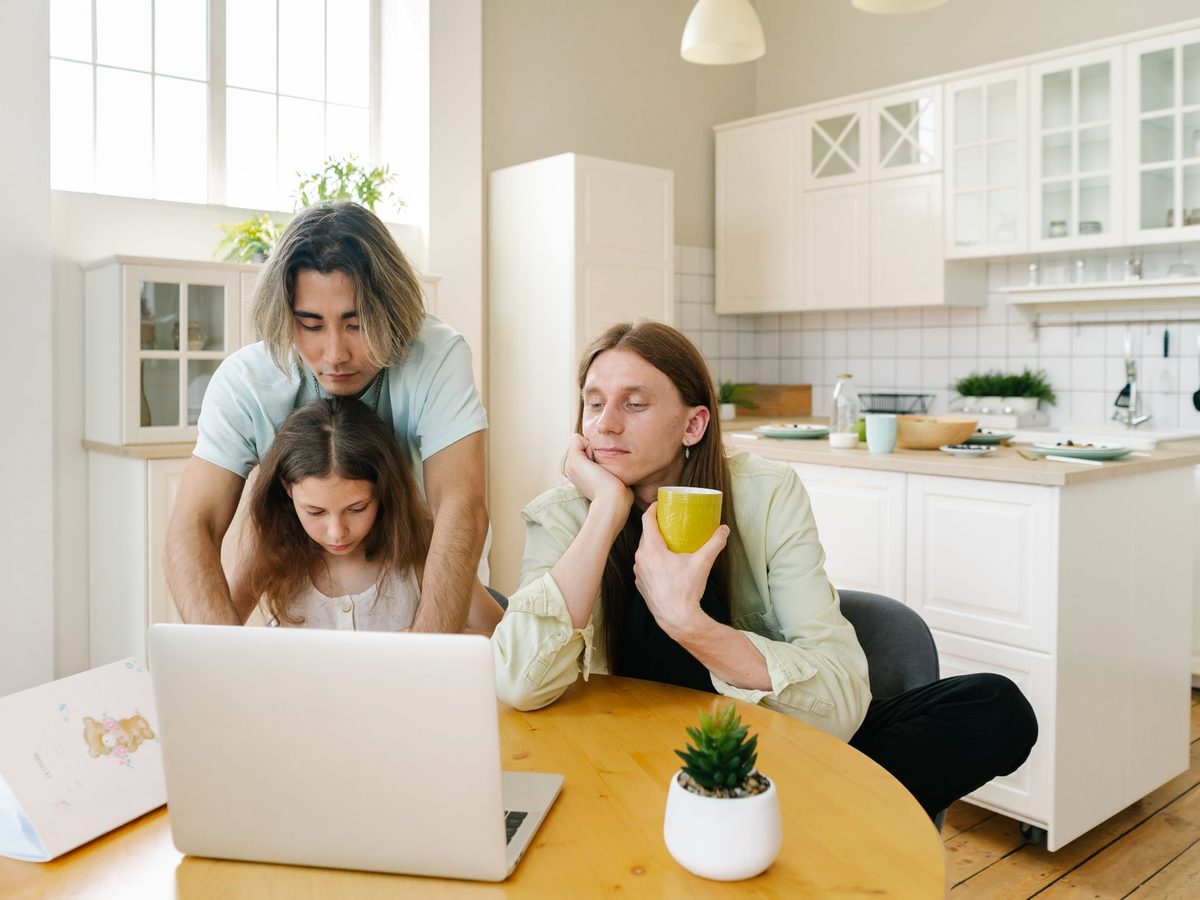A family at a kitchen bench looking at a laptop together